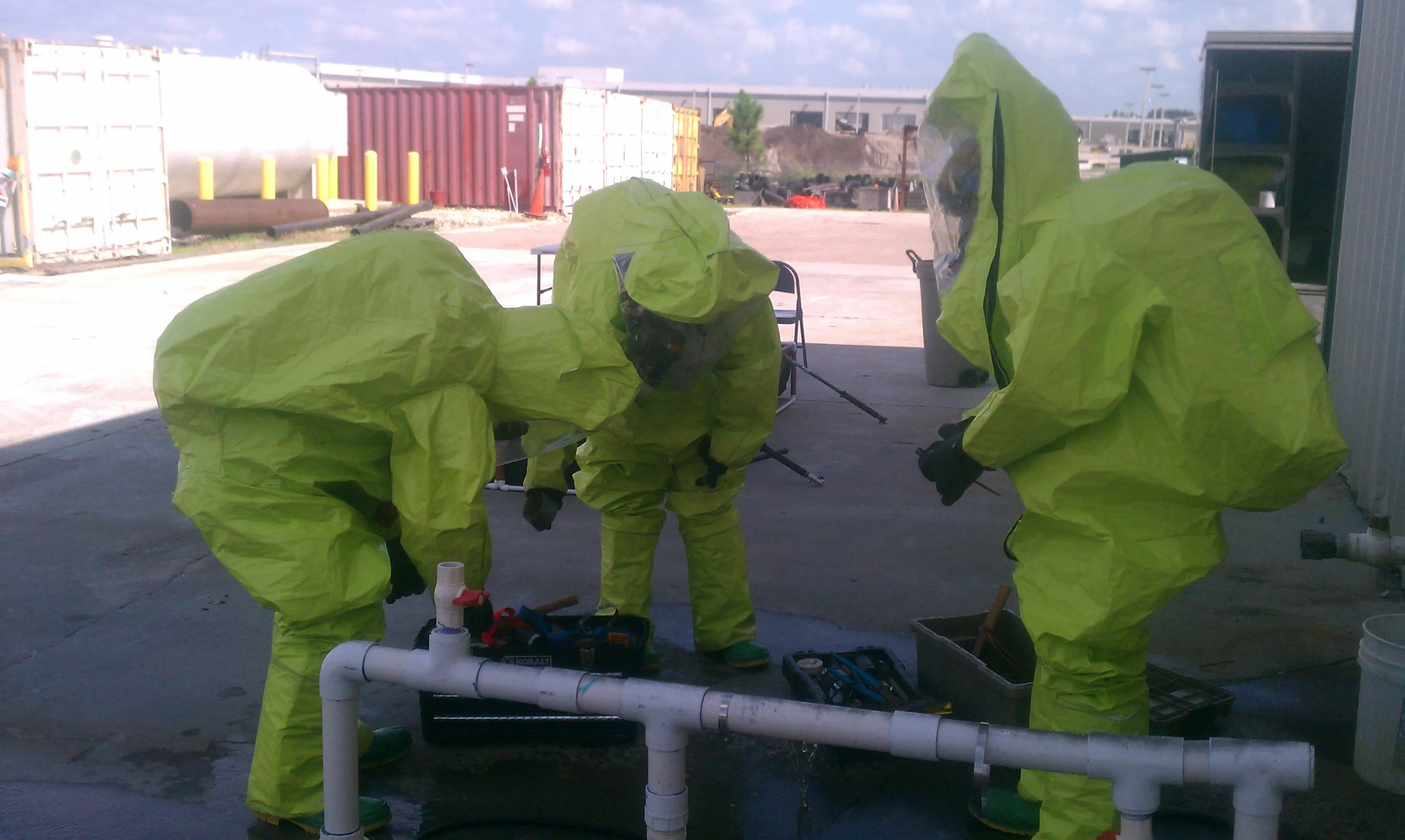 Responders in Level A chemical suits repairing a leaking pipe manifold during a hazmat drill